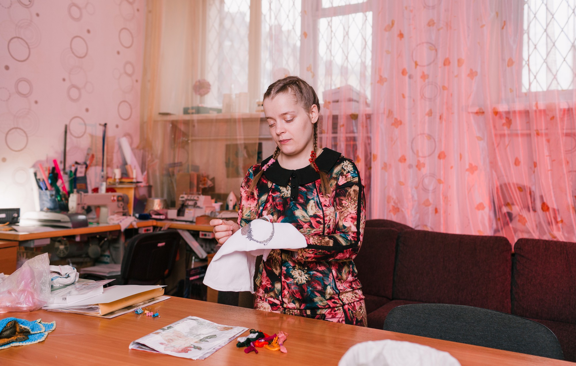 Amatininkė siuvinėja smulkią gėlės raidę